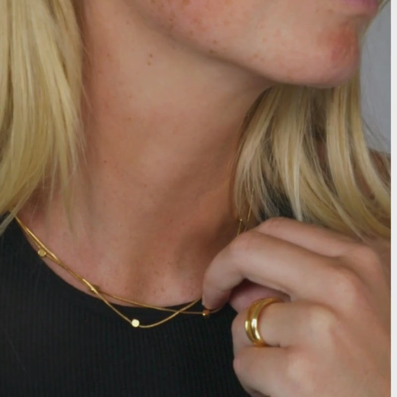 A striking double snake chain necklace featuring expressive square cube accents. Adjustable in length from 42cm to 47cm, it offers versatile styling options, whether worn long or short. Weighing 5.4g, this unique piece is crafted from durable, hypoallergenic stainless steel with 14k recycled gold. Resistant to rust, tarnishing, and skin discoloration, the necklace combines elegance with practicality for everyday wear.